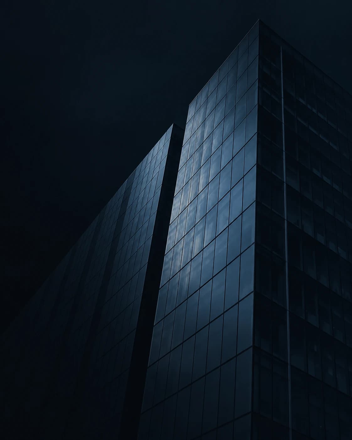 Dark glass institutional building seen from below.